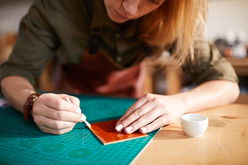 Close up portrait of female artisan tracing leather patterns while working in shoemaking atelier, copy space