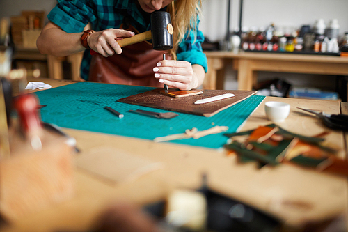 Warm toned portrait of unrecognizable female artisan making leather bag in atelier, copy space