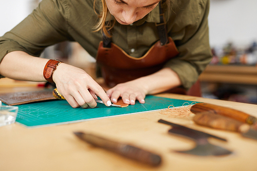 Cropped portrait of female craftsman working with leather in tannery shop, copy space