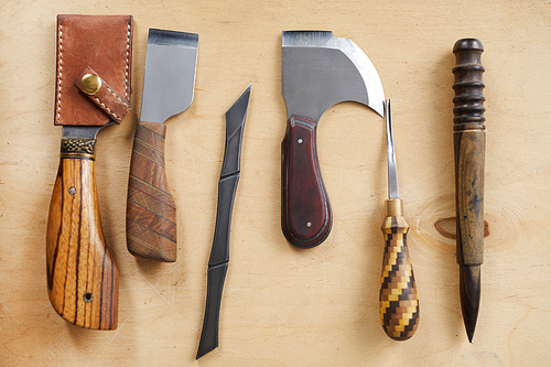 Top view background image of leatherworking tools lying on wooden table, copy space