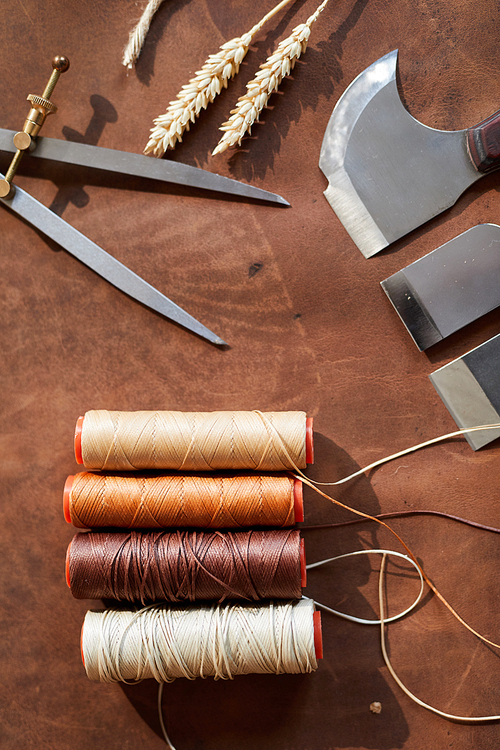 Top view background of leatherworking tools lying on wooden table in artisan atelier