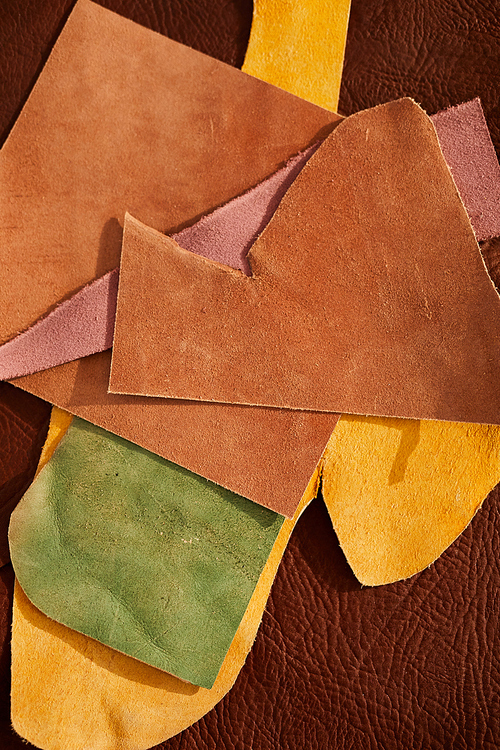 Top view background of colored leather pieces lying on table in leatherworking shop, copy space