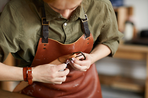 Mid section portrait of woman artisan making leather belt in leatherworking shop , copy space