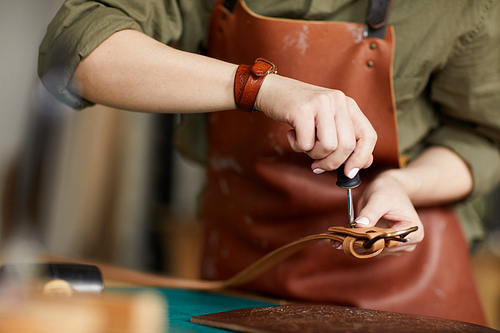 Mid section portrait of female artisan making leather belt in leatherworking shop , copy space