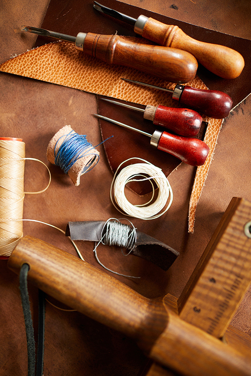 Background image of various tools lying on real leather in leatherworking shop, copy space
