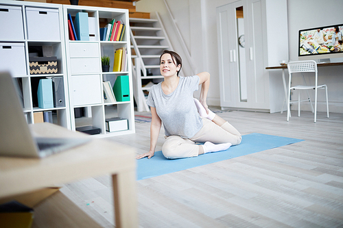 Full length portrait of contemporary young woman doing yoga exercises on mat at home, copy space