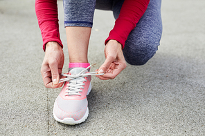 Closeup of unrecognizable woman tying sports shoes during morning run outdoors, copy space