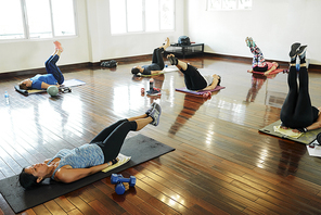 Group of young women exercising in gym together and strenghtening their abs