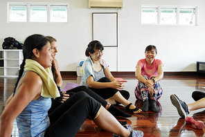 Group of cheerful young women talking and laughing after yoga class