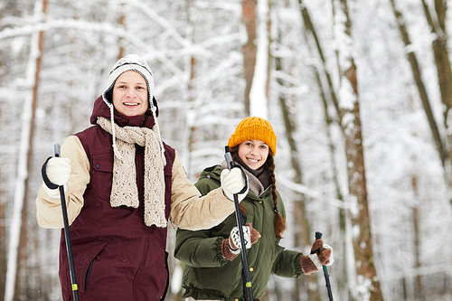 Waist up portrait of happy active couple skiing in forest and  enjoying winter, copy space