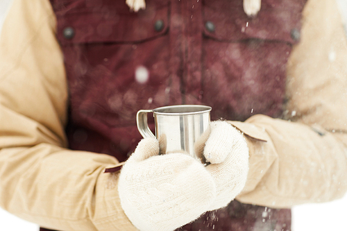 Closeup of unrecognizable man holding cup of hot cocoa outdoors enjoying hike in winter, copy space