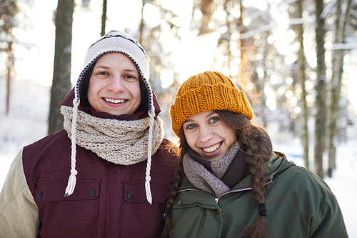 Portrait of happy young couple posing outdoors in beautiful winter forest, copy space