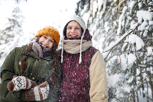 Waist up portrait of happy young couple posing outdoors in winter and smiling at camera, copy space