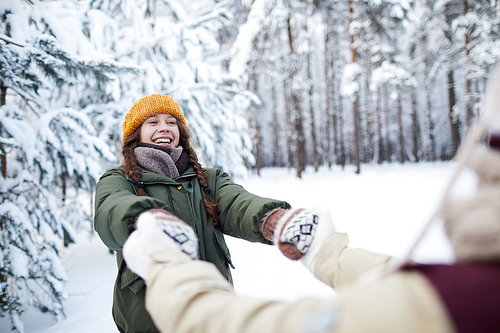 Waist up portrait of playful young couple having fun outdoors in winter and holding hands, copy space