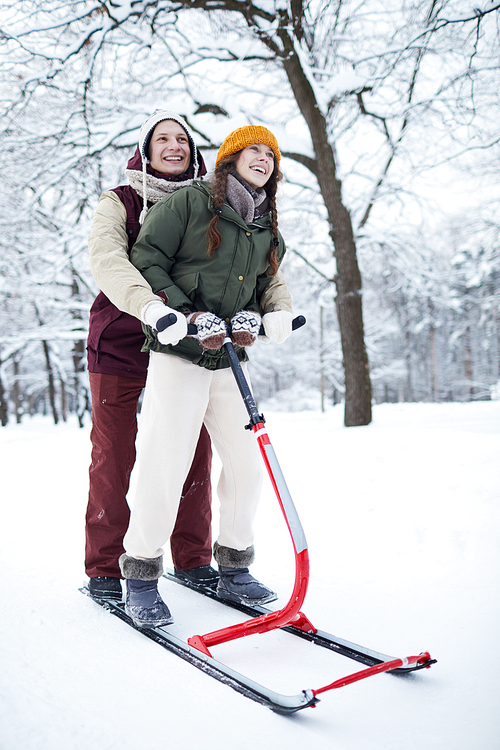 Full length portrait of happy young couple enjoying sleigh ride in beautiful winter forest