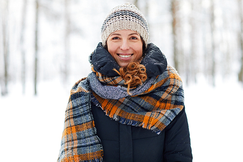 Waist up portrait of beautiful young woman in winter forest  and smiling, copy space