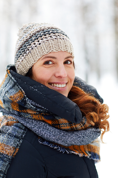 Head and shoulders  portrait of beautiful young woman in winter forest  and smiling