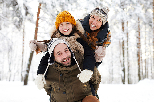 Portrait of playful happy family in winter forest  and smiling, copy space