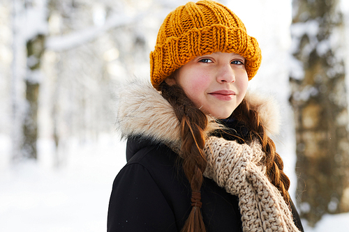 Head and shoulders portrait of smiling teenage girl in winter forest , copy space