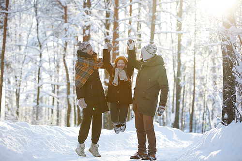Full length portrait of happy family having fun in beautiful winter forest, copy space