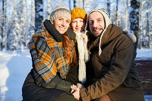 Portrait of loving family posing  in beautiful winter forest, copy space