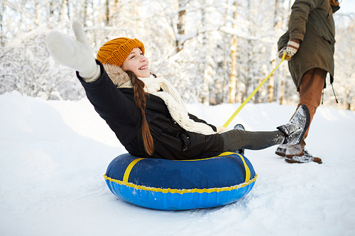 Full length portrait of happy girl enjoying sleigh ride in beautiful winter forest, copy space