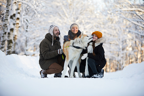 Portrait of happy family enjoying walk with dog in beautiful winter park, copy space