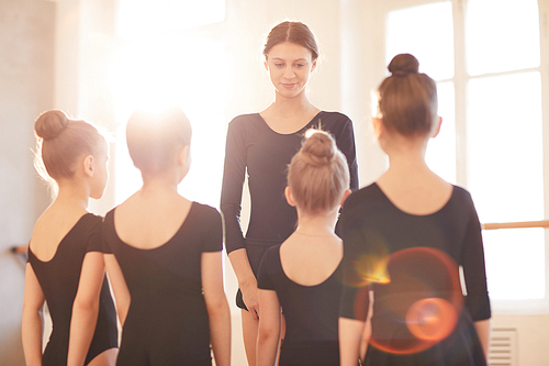 Portrait of ballet teacher talking to group of little girls in studio, copy space