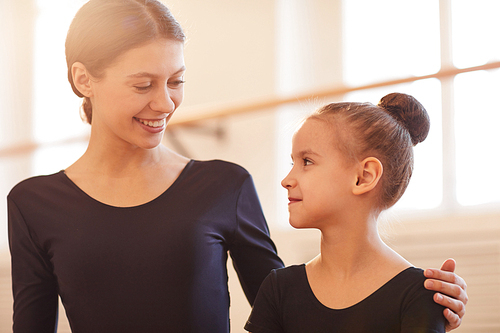 Portrait of young woman smiling at little girl in ballet class, copy space