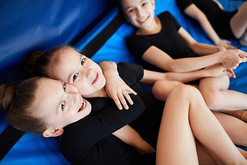 Happy  little girls smiling at camera while  lying on mats during dance or gymnastics practice
