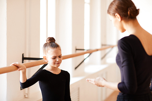 Portrait of little girl crying in ballet class with female teacher talking to her, copy space