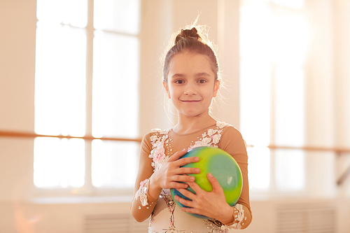 Waist up portriat of little gymnast posing  and holding ball, copy space