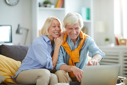 Portrait of happy mature couple using laptop while enjoying weekend at home , copy space