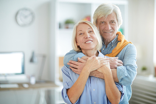 Waist up portrait of contemporary senior couple embracing tenderly , copy space