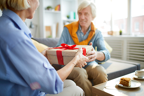 Mid section portrait of contemporary mature couple exchanging gifts at home, copy space