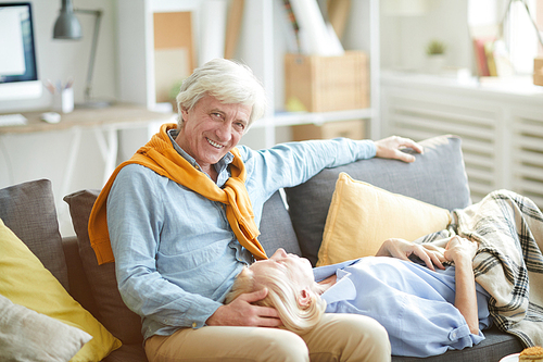Portrait of loving mature couple enjoying time together at home sitting on comfortable sofa, copy space