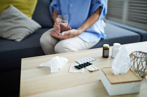 Close up of pills and various medication on table in front of unrecognizable senior woman, copy space