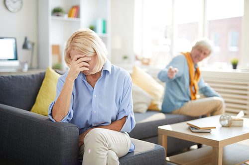 Portrait of modern senior couple fighting focus on crying senior woman in foreground, copy space