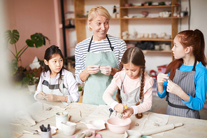 Portrait of smiling woman working with children in pottery class