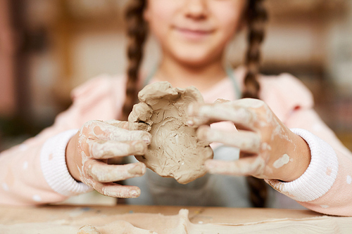 Closeup portrait of cute little girl making handmade ceramics in pottery class, copy space