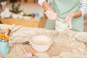 Closeup portrait of unrecognizable female artist shaping clay while working in pottery workshop, copy space