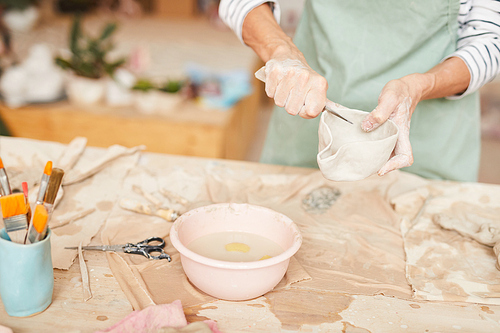 Closeup portrait of unrecognizable female artist shaping clay while working in pottery workshop, copy space