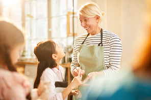 Portrait of smiling art teacher helping Asian girl in pottery class, copy space