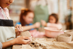 Closeup of unrecognizable little girl shaping clay in pottery class for children, copy space
