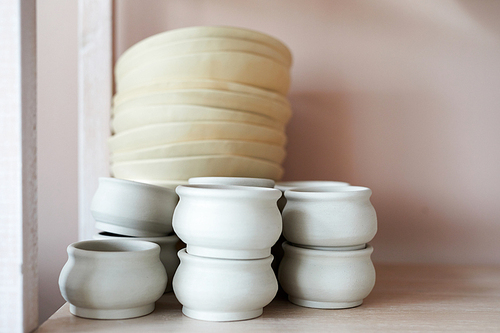 Background image of handmade ceramic bowls on shelf in pottery workshop, copy space