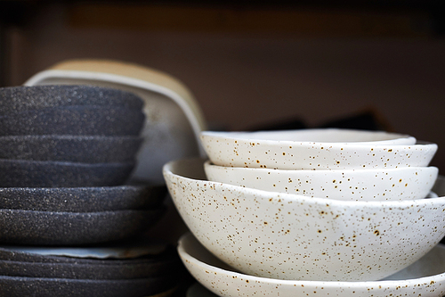 Side view closeup of handmade ceramic bowls on shelf in pottery workshop, copy space