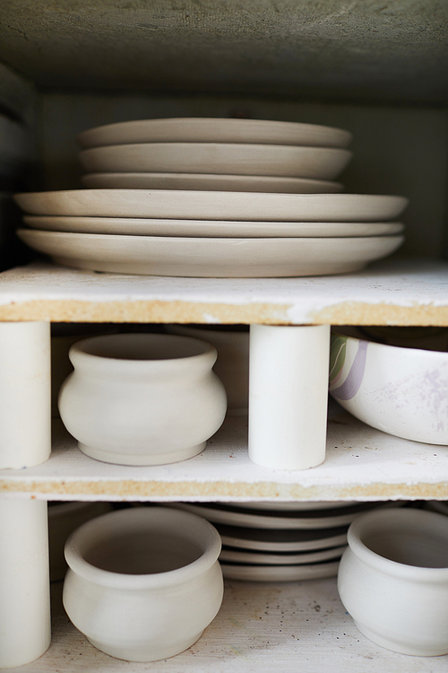 Background image of handmade ceramic items on shelf in pottery workshop, copy space