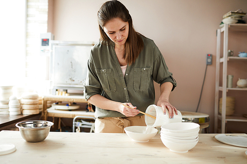 Waist up portrait of female ceramist working in pottery studio, copy space