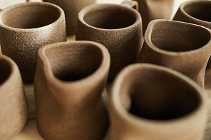 Closeup of handmade ceramic mugs in pottery shop, copy space
