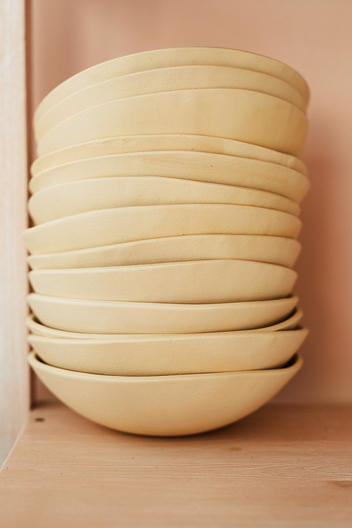 Closeup of rustic cupboard shelf with handmade bowls in stack, copy space
